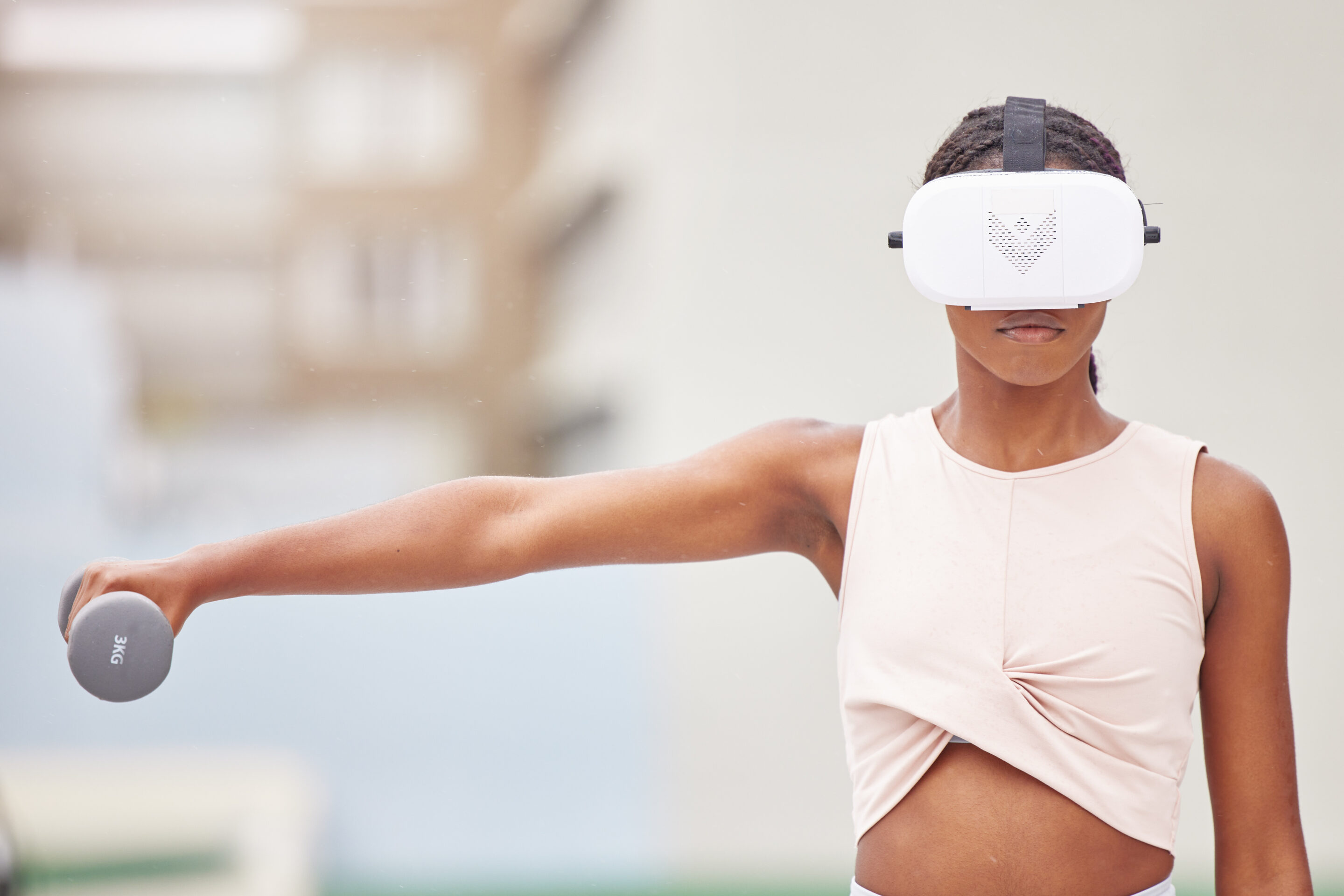 Frau trägt eine VR-Brille und streckt ihre Hand zur Seite, in der sich eine kleine Hantel befindet